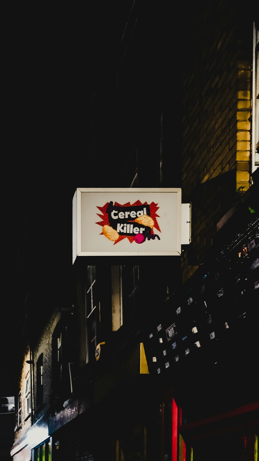 Colourful neon brand sign glowing at dusk on a European street